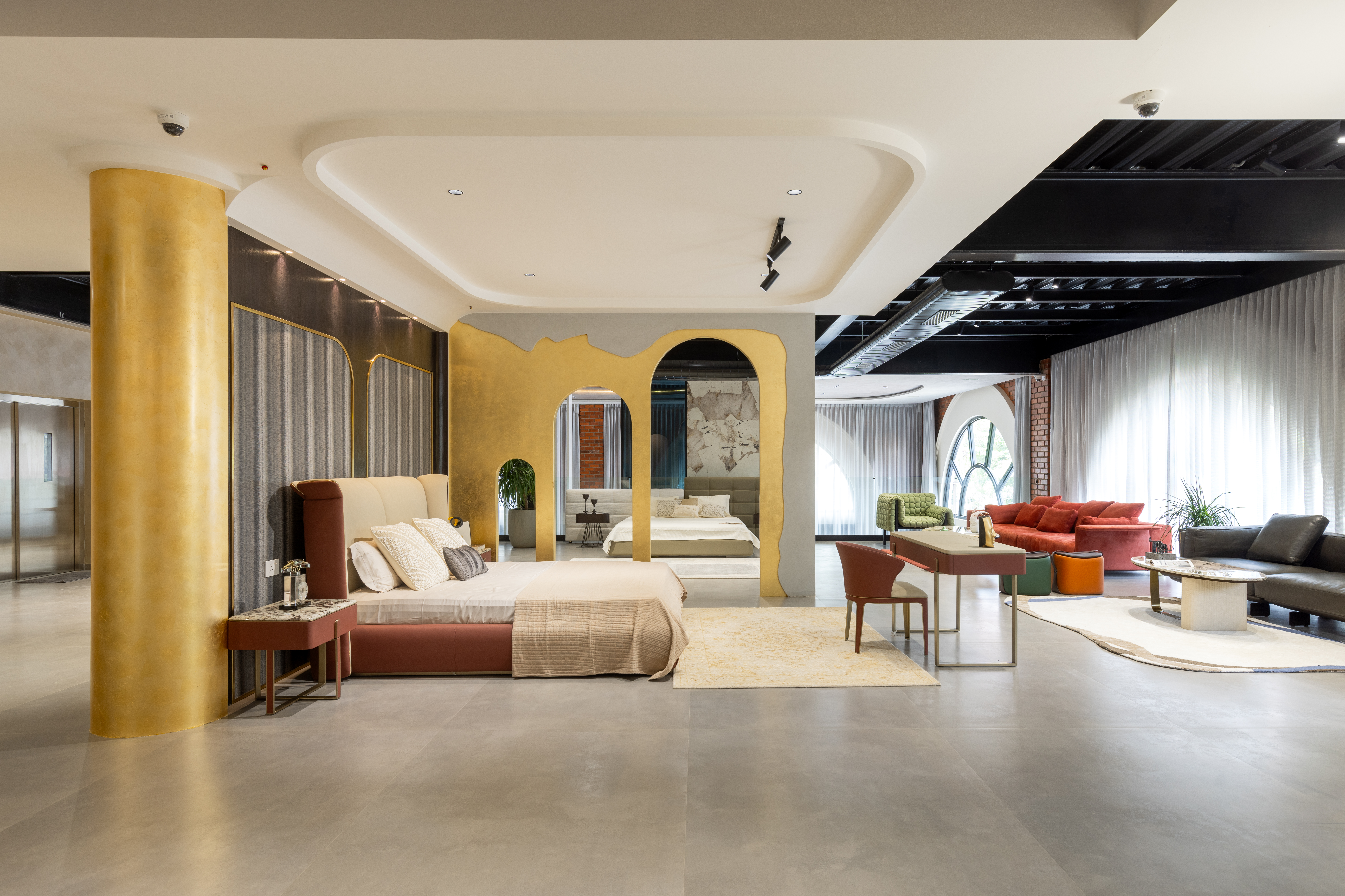 Entrance corner with an orange leather sofa, two tall white textured floor vases with dry branches, a dark three-lobed coffee table with a white sphere sculpture, on a sculpted cream rug against full-height curtains.